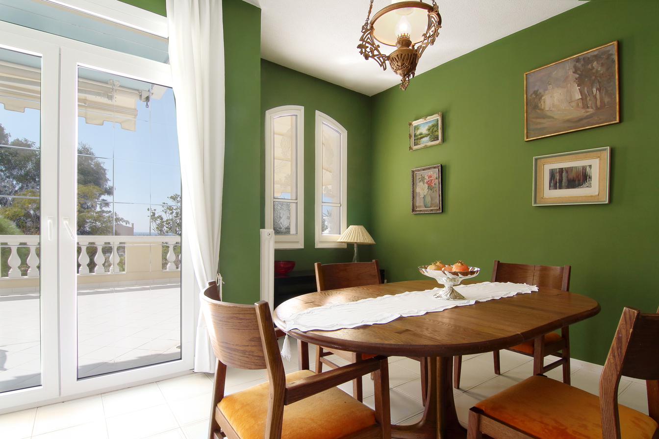 Dining room with green walls opening to the balcony
